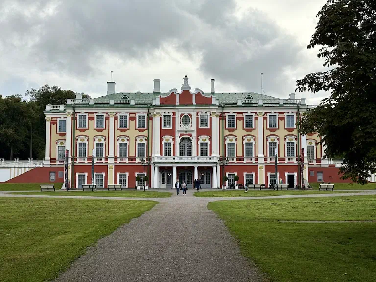 Das rot-gelbe barocke Schloss Kadriorg in Tallinn mit Rasenflächen und Kiesweg davor